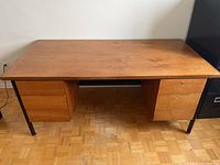 Front view of wooden desk showing two drawer units and metal legs on parquet floor