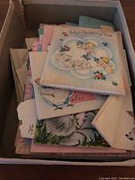 Box of assorted vintage baby and children's cards showing layered pastel-colored cards with classic illustrations and typography.