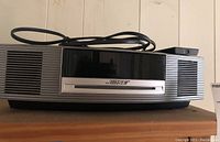 Front view of Bose Wave Music System showing sleek black and silver casing with power cable placed on top.