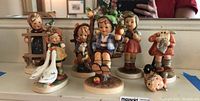 Full set of six Goebel porcelain figurines displayed on a mantel, showing variety of children and animal figures including geese and a lamb.