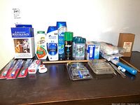 Full lot view showing all items including boxed Bed Buddy hot/cold pack, several bottles, toothbrushes, razors, floss, and cotton balls