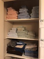 Shelves showing neatly folded stacks of towels in various pastel colors and several stacks of folded sheets including a leopard print sheet.