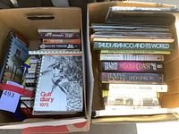 Top view of two boxes filled with assorted hard and soft cover books, titles visible including Gulf Diary 1975, Saudi Aramco and its World, Gold Coast by Nelson DeMille, Bedouin Jewelry signed by author