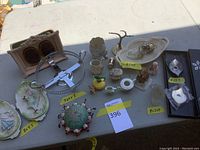 Top view of assorted ceramic decor including a porcelain egg, tiny pitchers, small bowls, picture frame, Asian style pin cushion, and Danish candle holders by Cohr, all arranged on a table.