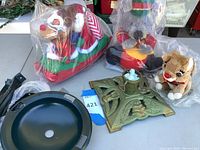 Photo showing plush Christmas characters including reindeer and mouse/rat, and metal Christmas tree stands.