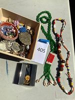 Lot of assorted ethnic and costume jewelry with beaded necklaces and assorted rings and brooches in box and displayed on surface