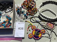 Top view of multiple beaded necklaces in a box including black, white, multicolor, and an intricate pendant necklace.