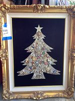 Full view of framed Christmas tree art with gold ornate frame, black velvet background and brooch collage tree