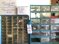 Full view of two multi-drawer storage boxes filled with various small hardware items, and three labeled cardboard boxes on top with caster wheels.