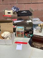 Overview of trays, desktop moistener, photo blocks, playing cards, box of index cards, candle holder, and glass boxes in the carton and on table