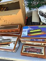 Photo showing various boxed Tyco train accessories including operating ore dump set, crossing gate, Chattanooga train car, and track pieces.