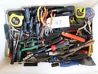 Top down close-up view of bin filled with assorted hand tools showing variety and condition.