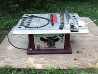 Delta 36-510C table saw showing overall view on plywood with power cord, fence, and safety guard resting on aluminum table top.