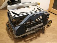 Fold-away table saw showing the power switch, metal foldable frame, visible rust and wear.