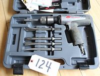 Open hard plastic case showing Ingersoll Rand percussive air hammer tool with six steel bits arranged in slots and a white tag with number 124.