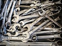 Close-up showing various imperial size combination wrenches piled together, with visible sizes and made of drop forged steel.