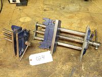 Photo showing two Mastercraft bench clamps on a wooden surface, one large with dual threaded rods and one smaller with single threaded rod.