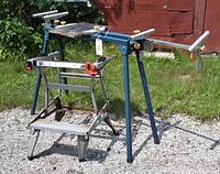 Front and side view of the blue metal portable workmate bench with wooden top and a gray metal workmate bench with red clamps showing wear and rust.