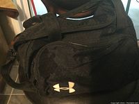 Front side of black Under Armour duffel bag showing logo and front pocket.