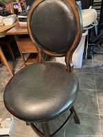 Photo of swivel bar stool showing wooden frame with black faux leather cushioned seat and backrest