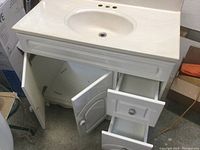 White bathroom vanity with open cabinet doors and drawers showing storage space