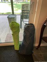 Two camping bags, one large black bag containing a dome tent, and a smaller green bag containing a beach chair.