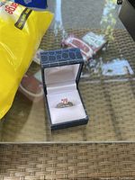 Silver-tone ring with clear pink stone in blue jewelry box on glass surface