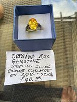 Sterling silver ring with large oval citrine gemstone and colored marcasite on the sides, handwritten note showing size 6 and price.