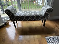 Front view of a grey upholstered bench with off-white trellis pattern and rolled arms.