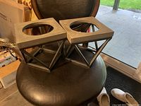 Two wooden geometric dog bowl holders shown side-by-side on a chair, no bowls inside.