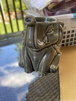 Front side view of the elephant-shaped ceramic plug-in warmer on a table with outdoor background.