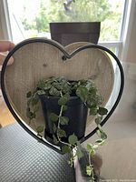 Heart-shaped wooden and metal hanging plant hanger with a small plant pot inside.