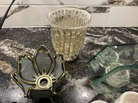 Photo showing clear textured glass jug and tinted glass candle holder with gold trim