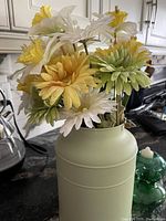 Close-up of silk flowers in one mint green milk can holder showing yellow and white flowers with green accents