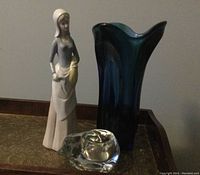 Photo of all three items: blue glass vase, cat votive holder, and woman statue displayed together on a surface.
