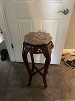 Full view of mahogany plant stand showing octagonal marble top, carved apron, and gracefully curved legs.