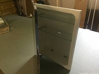 Front view of the white metal medicine cabinet with mirrored door closed showing smooth edges and size.