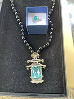 Photo of Heidi Daus black beaded necklace with large aqua-blue rectangular stone pendant and matching ring with round aqua-blue stone in a box