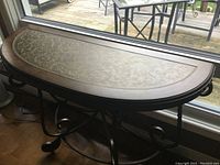 Semi-circular table top with embossed floral pattern under window