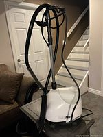 Full view of the Steam Fast clothing steamer unit including the base, hose, stand, and nozzle, placed on a small table.