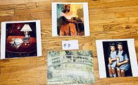 Four unframed art prints laid out on hardwood floor showing a variety of subjects.