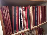 Shelf of mostly thin hardcover cooking/entertaining magazines and books with maroon and red spines