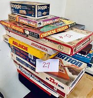 Stacked boxes of various board games including Boggle, Master Minds, Chinese Checkers, Avalanche, and Concentration with visible wear