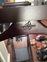 Close-up image of dark wood clothing hanger branded 'Ampersand'.
