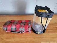 Doc Martens shoe shine kit in a plaid zippered bag and accompanying black cylindrical container with yellow interior.