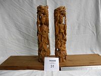 Front view of two carved wooden Chinese figures with a measuring ruler showing height approximately 12 inches.