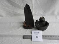 Two cast iron incense holders side by side with ruler for scale, photographed on white cloth background