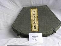 Closed green fabric octagonal case with Chinese characters on label