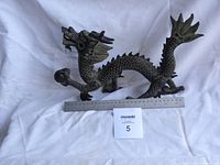 Full side view of Chinese dragon statue with ruler for scale, showing length and design details
