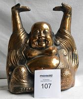 Front view of the copper Buddha figure with a joyful face and raised arms.